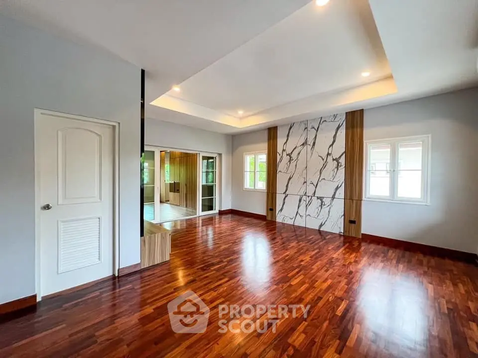 Spacious modern living room with hardwood floors and elegant marble accent wall.
