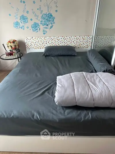 Cozy bedroom with modern decor and floral wall art, featuring a comfortable bed and stylish furnishings.