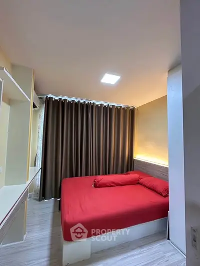 Cozy bedroom with red bedding and modern lighting, perfect for relaxation and comfort.