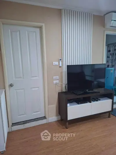 Modern living room with TV and stylish decor, featuring wood flooring and elegant wall paneling.