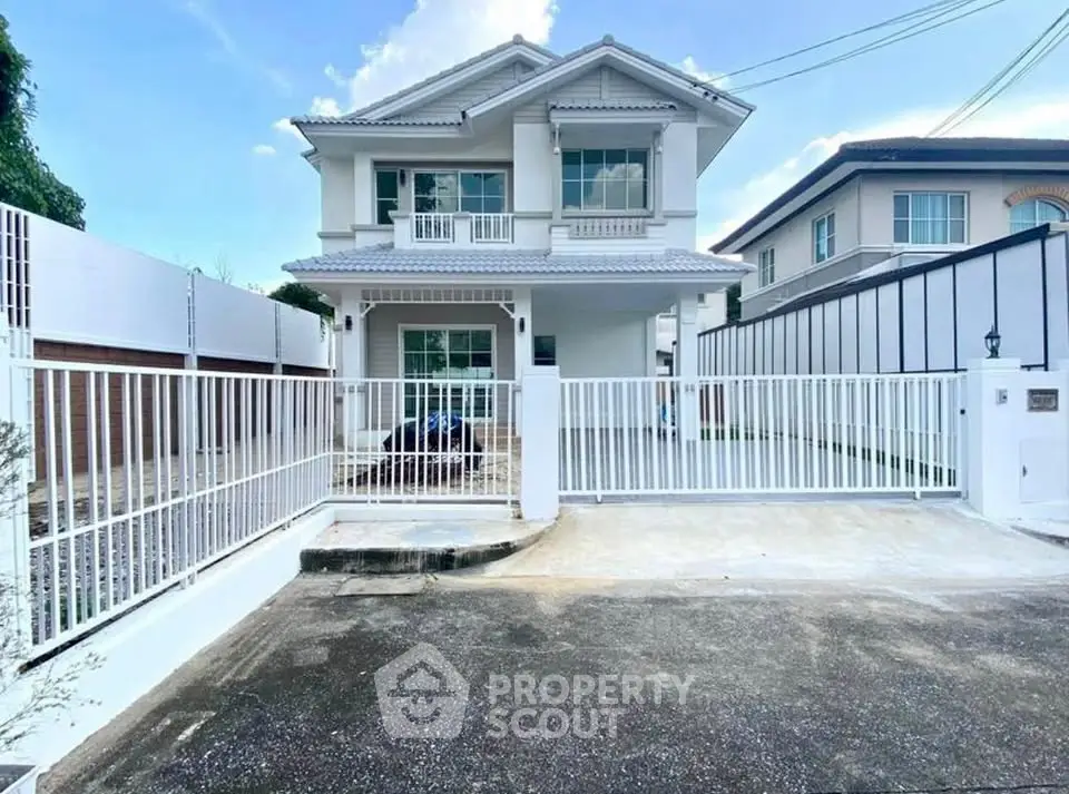 Charming two-story house with spacious driveway and modern white fence in a serene neighborhood.