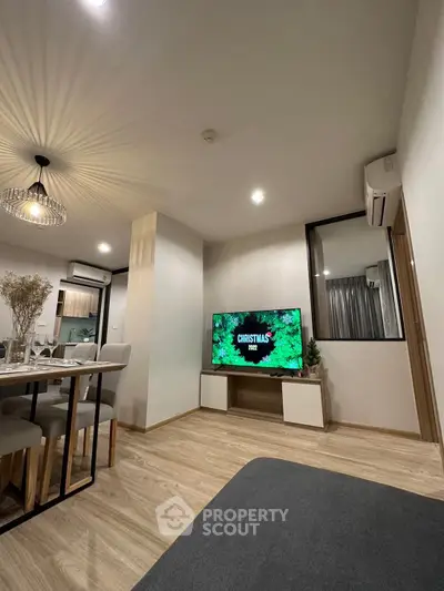 Modern living room with stylish decor and dining area, featuring a flat-screen TV and elegant lighting.