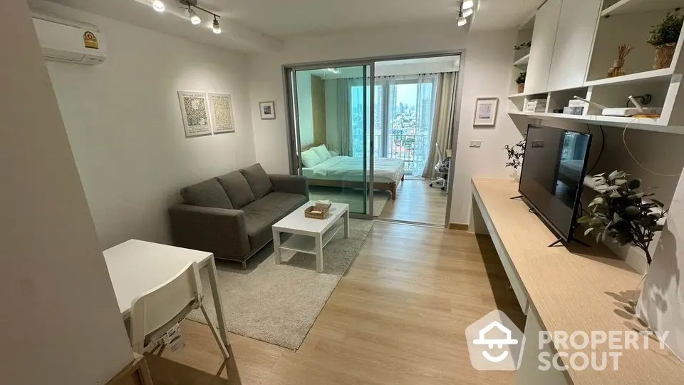 Modern studio apartment with open living area and city view, featuring sleek furniture and natural light.