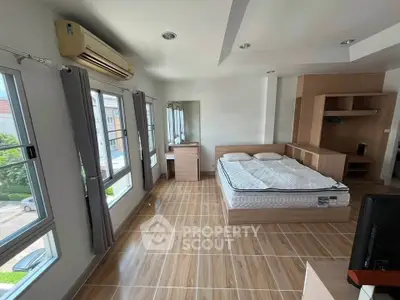 Spacious bedroom with modern furnishings and large windows offering natural light.
