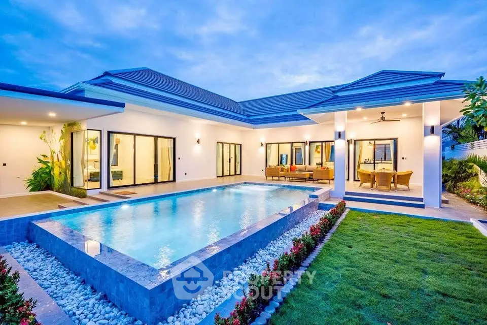 Luxurious modern villa with stunning pool and landscaped garden at dusk.