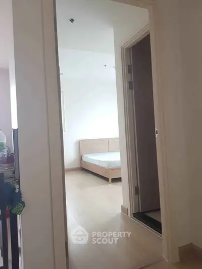 Bright bedroom with minimalist wooden bed and open doorway view.