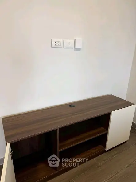 Modern wooden cabinet against a white wall in a minimalist interior space.
