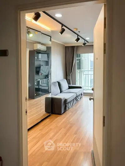 Modern living room with wooden flooring and large windows in a stylish apartment.