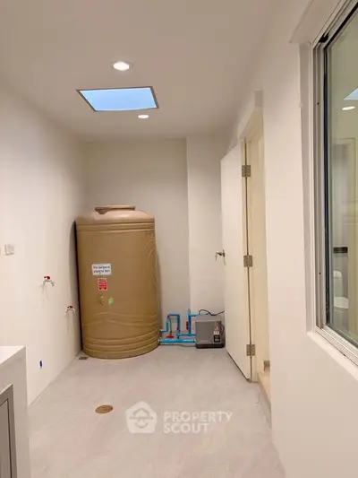 Spacious utility room with water tank and modern fixtures, ideal for efficient home management.
