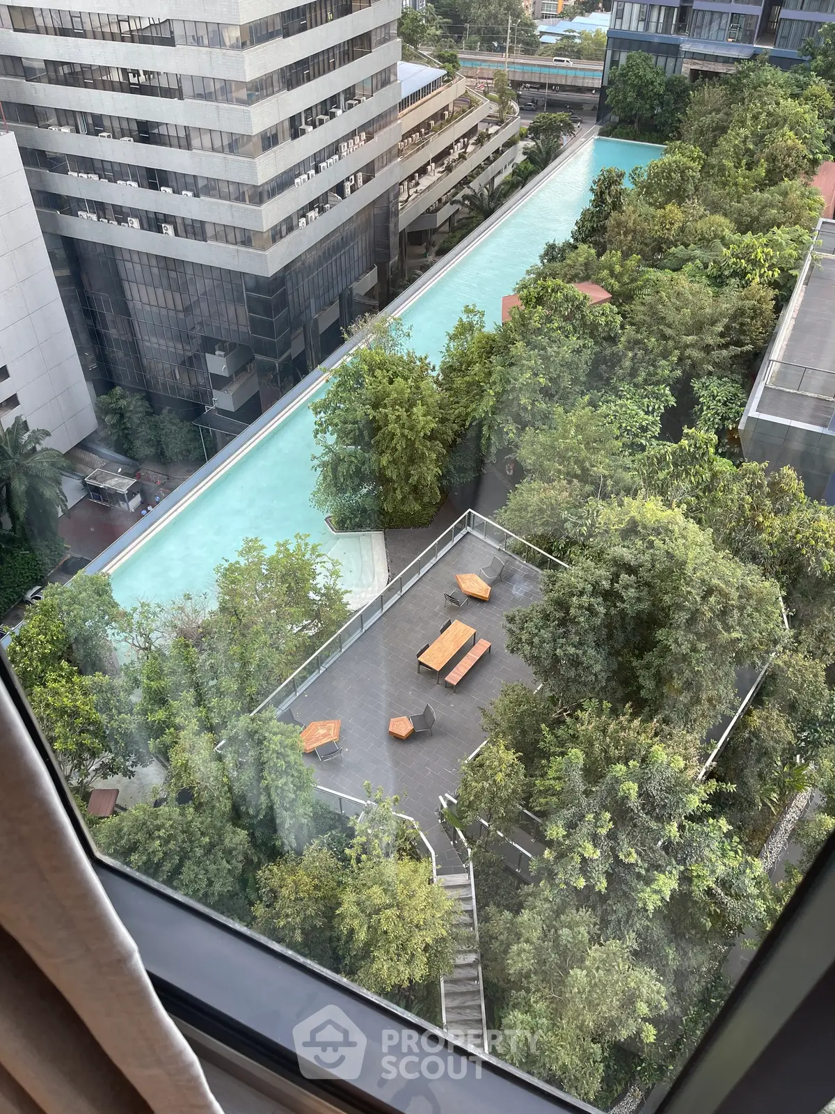 Stunning aerial view of modern building with lush greenery and pool, perfect for urban living.