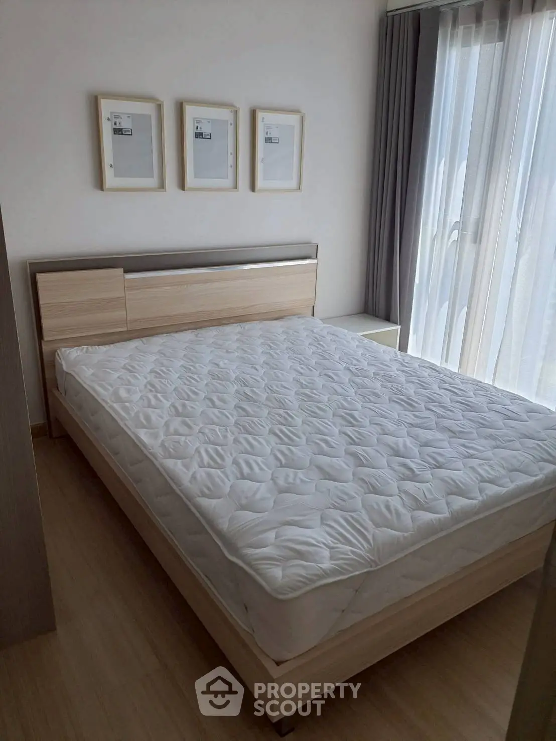 Modern bedroom with natural light and minimalist decor, featuring a comfortable bed and stylish frames.