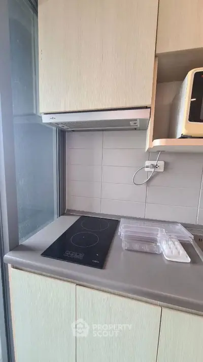 Modern kitchen with sleek electric stove and microwave in compact space.