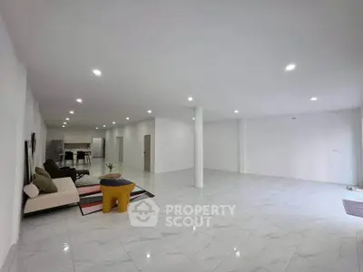 Spacious open-plan living room with modern kitchen and elegant tile flooring.