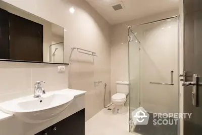 Sleek modern bathroom with glass shower enclosure, wall-mounted sink, and large mirror, perfect for contemporary urban living.