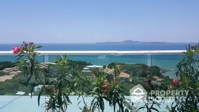 Stunning ocean view from a modern balcony with glass railing and lush greenery.