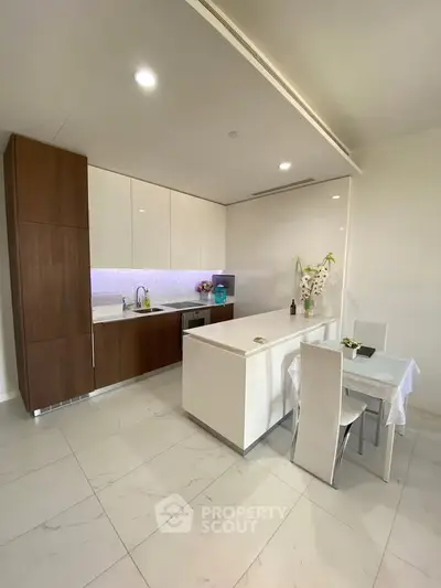 Modern kitchen with sleek cabinetry and dining area in a bright, open space.