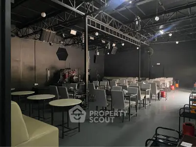 Spacious event venue with modern seating and stage area, perfect for gatherings and performances.
