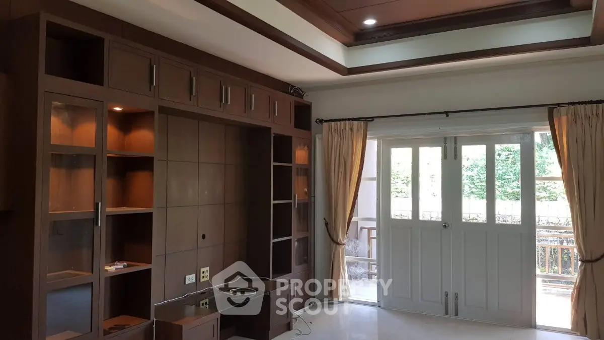 Spacious living room with built-in wooden shelves and large windows for natural light.