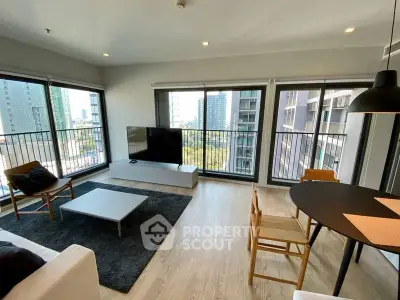 Modern living room with large windows and city view, featuring stylish furniture and open layout.