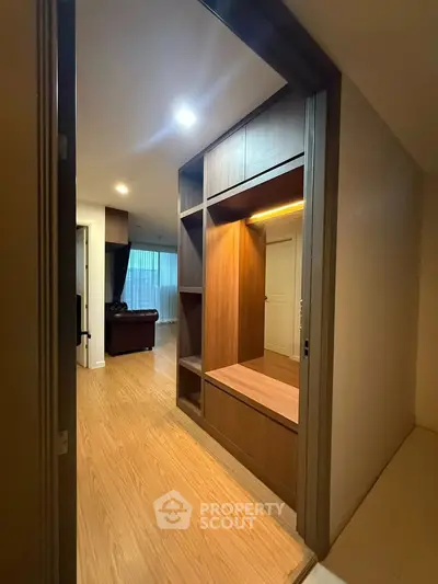 Stylish modern apartment entrance with wooden storage and cozy living room view.