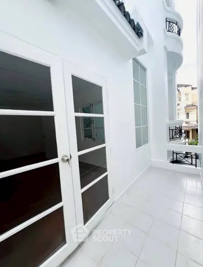 Charming white balcony with elegant glass doors and stylish railings in a modern home.