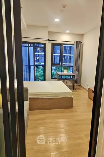 Modern bedroom with large windows and wooden flooring in a stylish apartment.