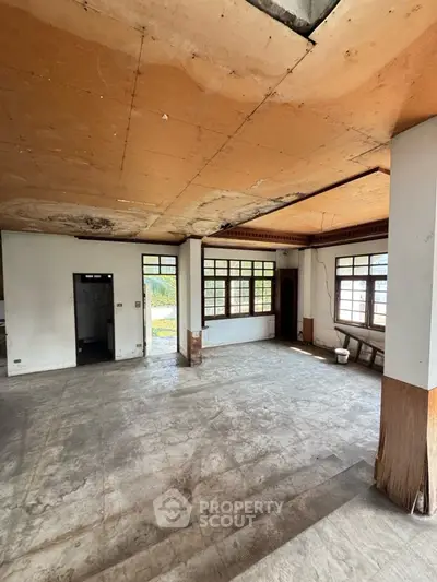 Spacious interior with large windows and potential for renovation