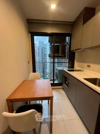 Modern kitchen with city view, sleek cabinetry, and dining area in high-rise apartment.