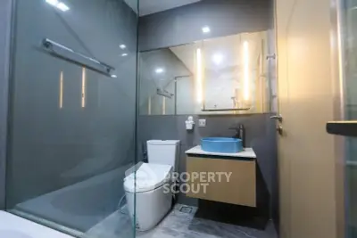 Modern bathroom with sleek design, glass shower, and stylish lighting