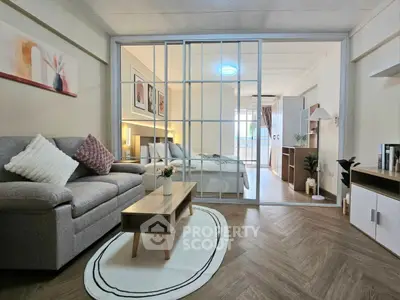 Modern studio apartment with cozy living area and stylish bedroom separated by glass doors.