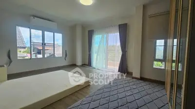 Spacious bedroom with large windows and balcony access, offering natural light and scenic views.