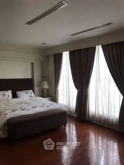Spacious bedroom with elegant curtains and polished wooden floors