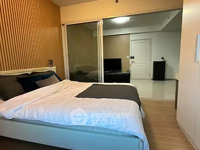 Modern bedroom with stylish wood paneling and cozy bedding in a contemporary apartment.
