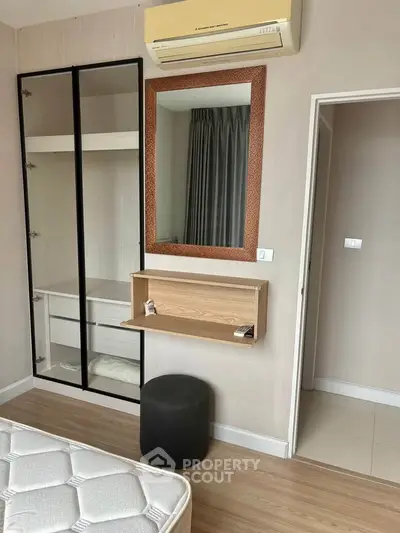 Modern bedroom with built-in wardrobe, air conditioning, and stylish mirror in a cozy apartment.