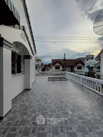 Spacious tiled balcony with elegant railing and scenic neighborhood view.