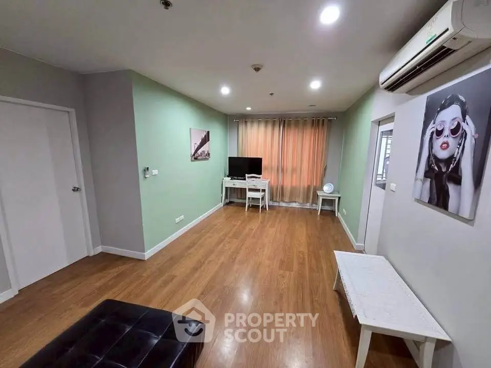 Spacious living room with modern decor and hardwood floors, featuring a wall-mounted TV and stylish artwork.