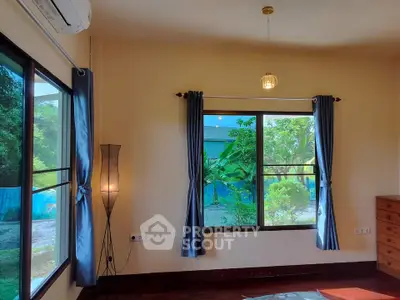 Bright bedroom with large windows and garden view, featuring elegant curtains and a stylish floor lamp.