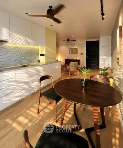 Modern open-layout kitchen and dining area with stylish furniture and warm lighting.