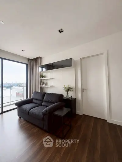 Modern living room with sleek black sofa and large window offering city view
