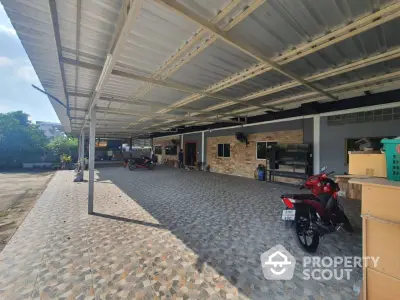 Spacious covered parking area with tiled flooring and motorbikes, ideal for residential or commercial use.