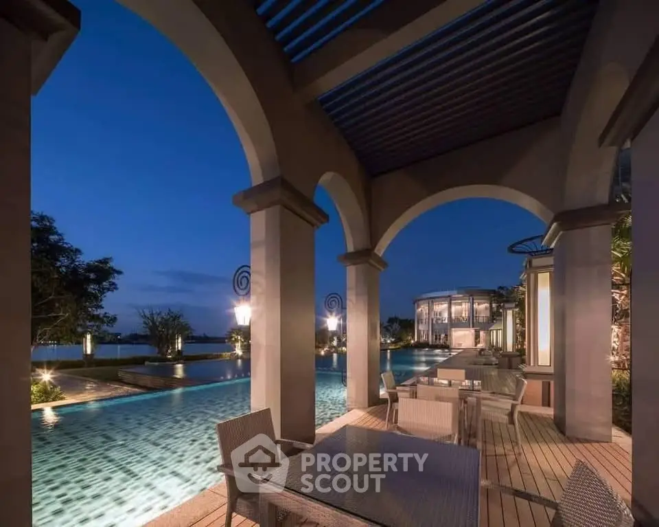 Luxurious poolside dining area with elegant arches and serene evening ambiance.