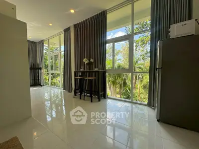 Spacious living area with large windows offering lush garden views, perfect for relaxation and entertaining.