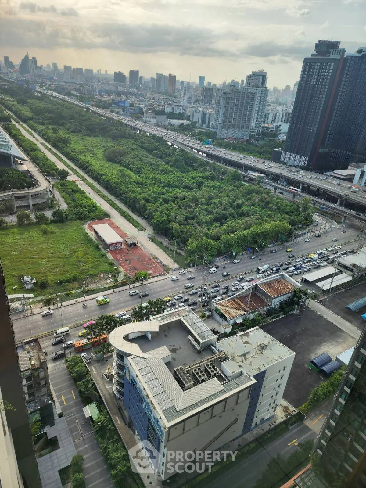 Stunning cityscape view from high-rise building overlooking lush green park and urban skyline.