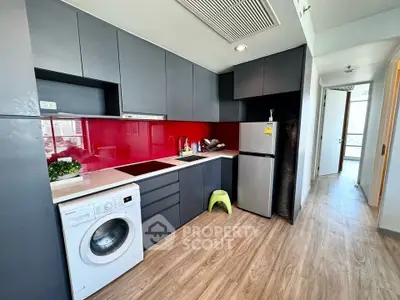 Modern kitchen with sleek cabinets, red backsplash, and in-unit washing machine.
