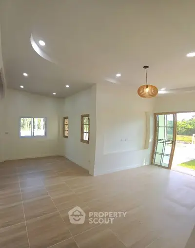 Spacious living room with modern lighting and large windows for natural light.
