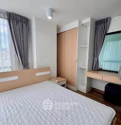 Modern bedroom with large window and built-in wardrobe in a high-rise apartment.