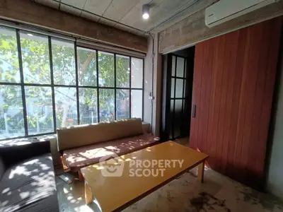 Chic industrial-style living room with large windows and cozy seating area.