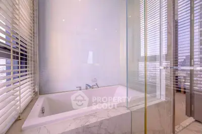 Luxurious bathroom with marble bathtub and large windows for natural light.