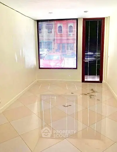 Spacious empty room with large window and tiled floor, ideal for customization.