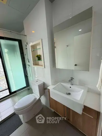 Modern bathroom with sleek fixtures and glass shower enclosure in contemporary home.
